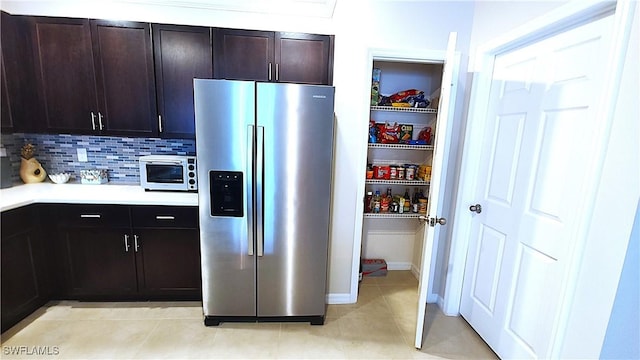 kitchen with dark brown cabinetry, stainless steel fridge with ice dispenser, decorative backsplash, and light tile patterned floors