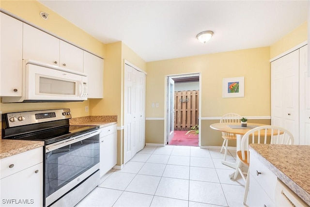 kitchen featuring light tile patterned flooring, white cabinets, and stainless steel electric range