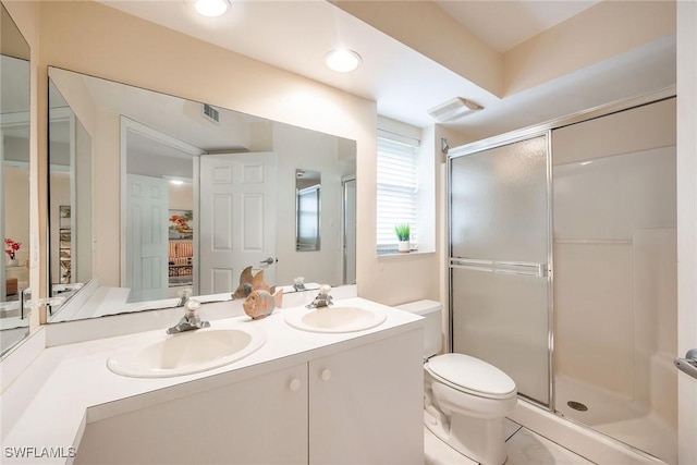 bathroom featuring vanity, a shower with shower door, and toilet