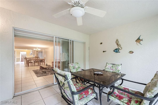 tiled dining room with ceiling fan with notable chandelier and a textured ceiling