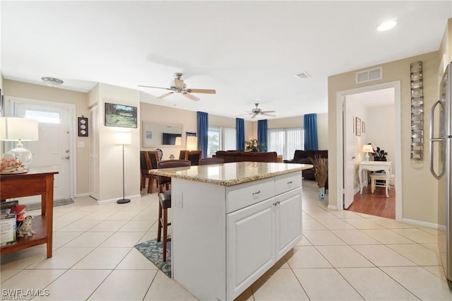 kitchen featuring a breakfast bar area, a center island, light tile patterned floors, and white cabinets