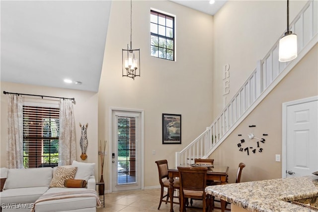 dining room featuring a notable chandelier, light tile patterned flooring, and a high ceiling