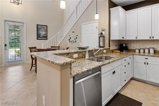 kitchen featuring pendant lighting, white cabinetry, stainless steel dishwasher, and kitchen peninsula