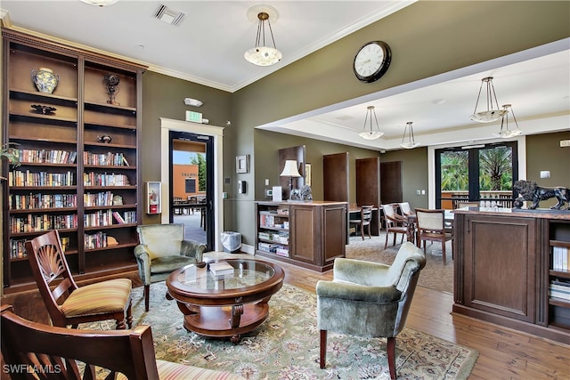 sitting room featuring french doors, crown molding, and light hardwood / wood-style flooring