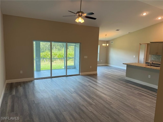 unfurnished living room featuring lofted ceiling, sink, ceiling fan with notable chandelier, and dark hardwood / wood-style floors