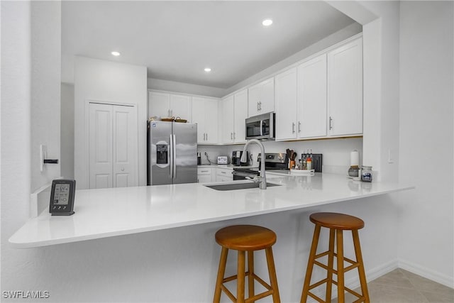 kitchen with appliances with stainless steel finishes, sink, white cabinets, and kitchen peninsula