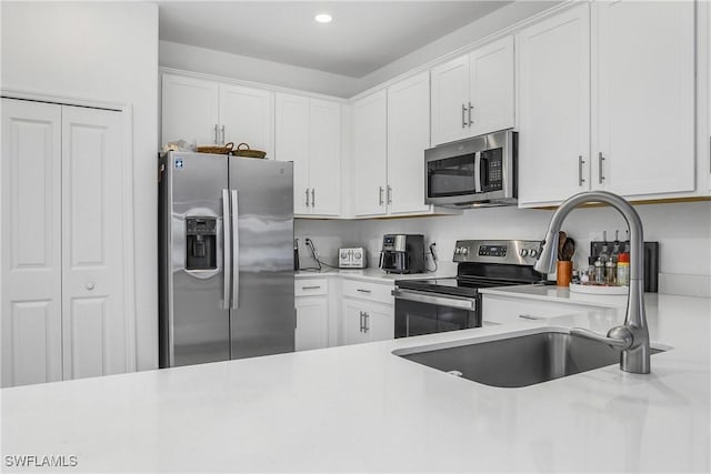 kitchen featuring stainless steel appliances, white cabinetry, and sink