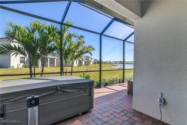 view of patio featuring a lanai, a hot tub, and a water view