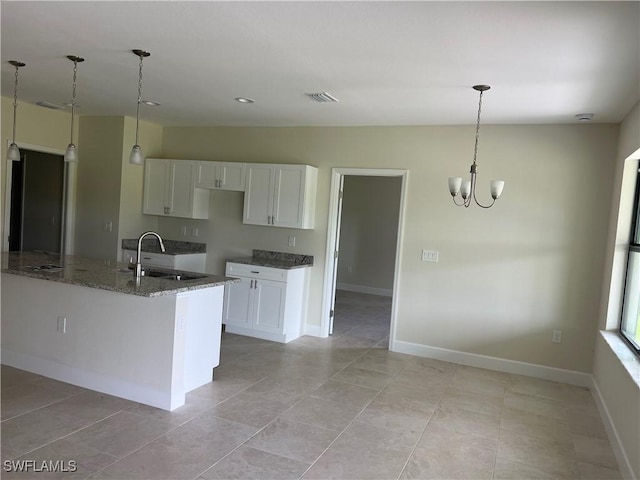 kitchen featuring white cabinetry, dark stone counters, light tile patterned flooring, and sink