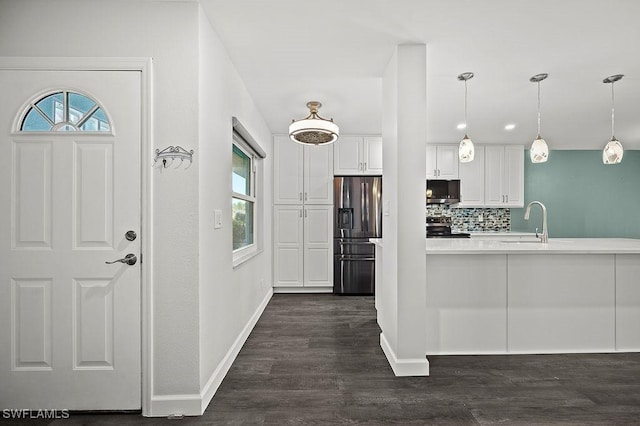 kitchen featuring appliances with stainless steel finishes, tasteful backsplash, hanging light fixtures, dark wood-type flooring, and white cabinetry