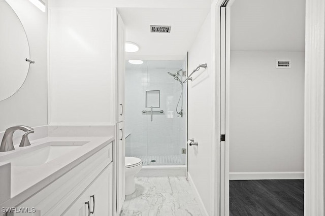 bathroom with toilet, vanity, and a shower with shower door