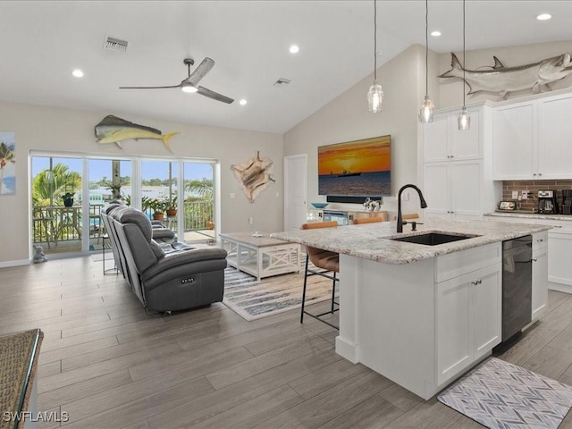 kitchen featuring a sink, visible vents, white cabinets, light stone countertops, and light wood finished floors