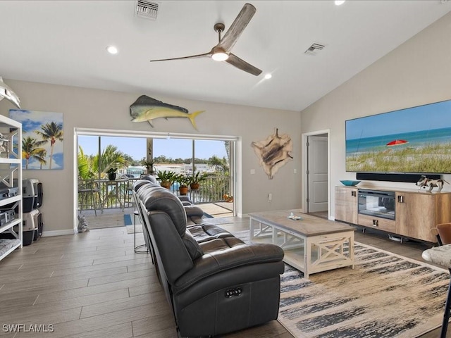 living room featuring lofted ceiling, a ceiling fan, visible vents, and wood finished floors