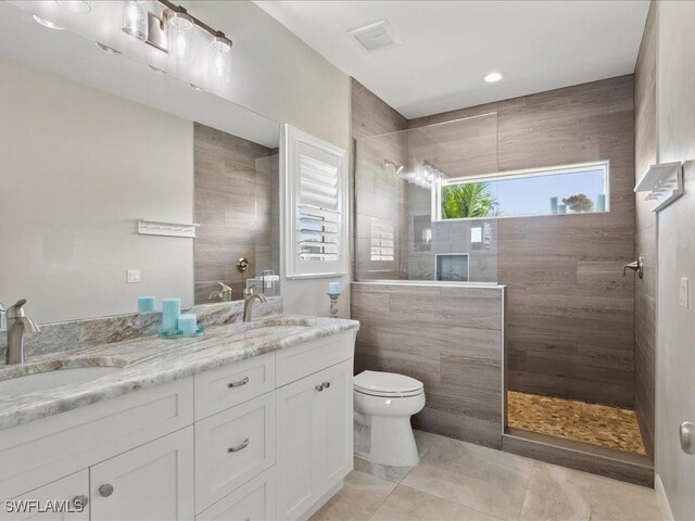 full bathroom featuring double vanity, a walk in shower, toilet, and a sink