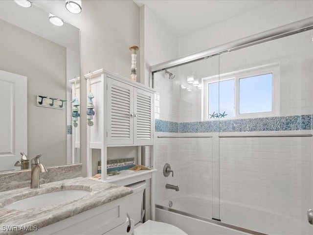 bathroom with bath / shower combo with glass door, vanity, and toilet