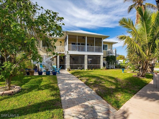 back of house with stairway, a lawn, a ceiling fan, and a sunroom