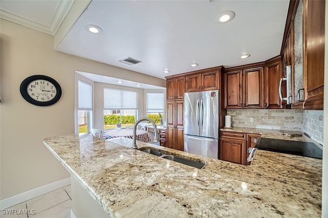 kitchen with tasteful backsplash, sink, stainless steel fridge, range, and light stone countertops