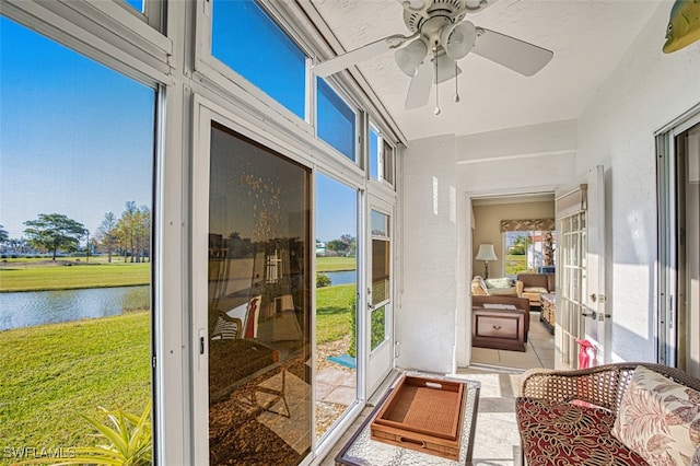 sunroom / solarium featuring a wealth of natural light, ceiling fan, and a water view