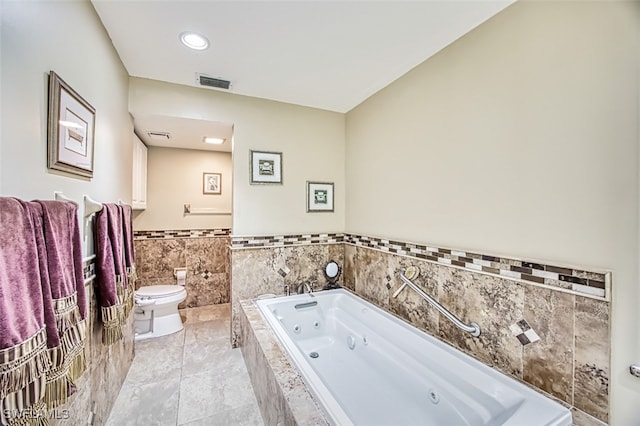 bathroom featuring a relaxing tiled tub, tile patterned floors, tile walls, and toilet