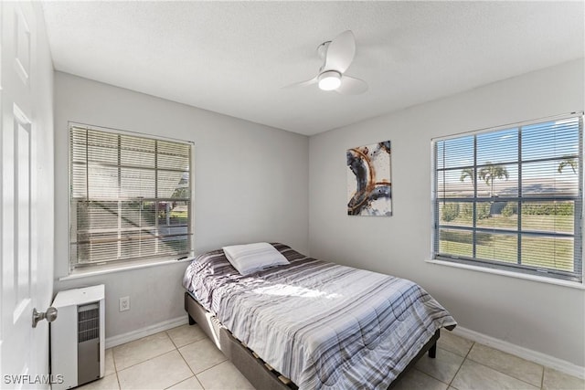 bedroom with ceiling fan, light tile patterned floors, and a textured ceiling