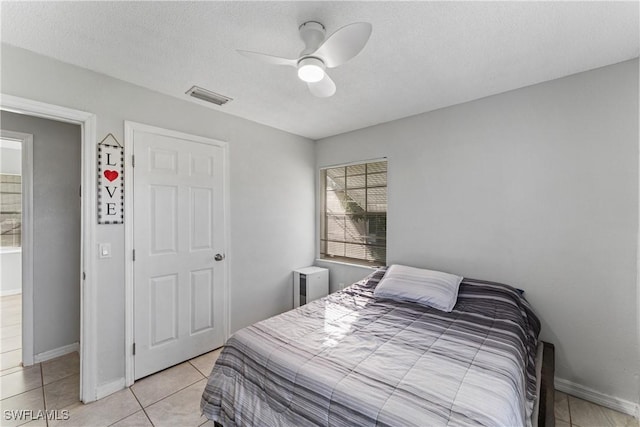 tiled bedroom featuring ceiling fan and a textured ceiling