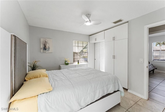 tiled bedroom with ceiling fan and a closet