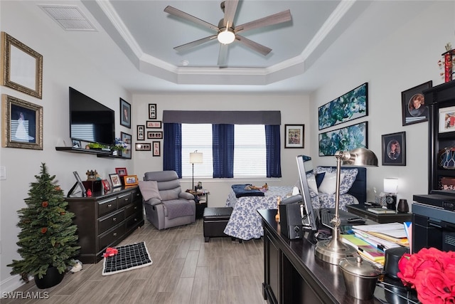 office with crown molding, ceiling fan, light hardwood / wood-style floors, and a tray ceiling