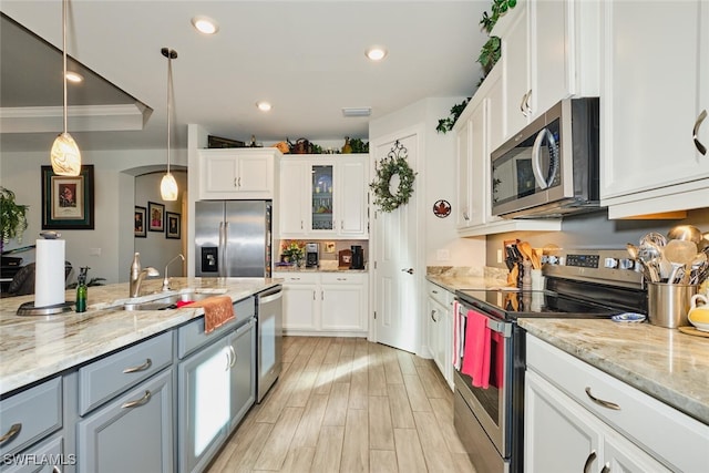 kitchen with pendant lighting, appliances with stainless steel finishes, sink, and white cabinets