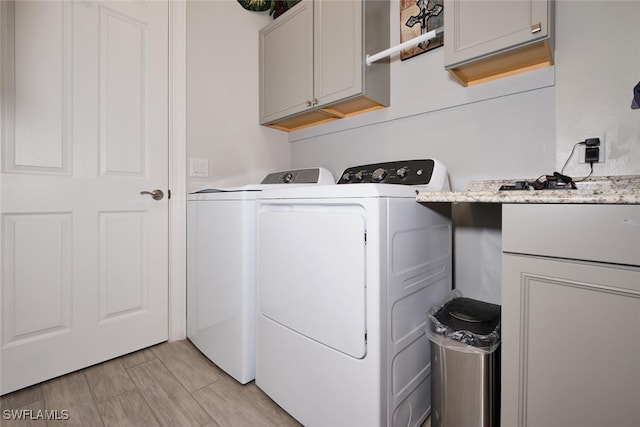 laundry room with cabinets, washer and clothes dryer, and light wood-type flooring