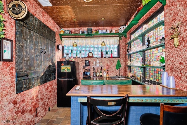 bar featuring black refrigerator and sink