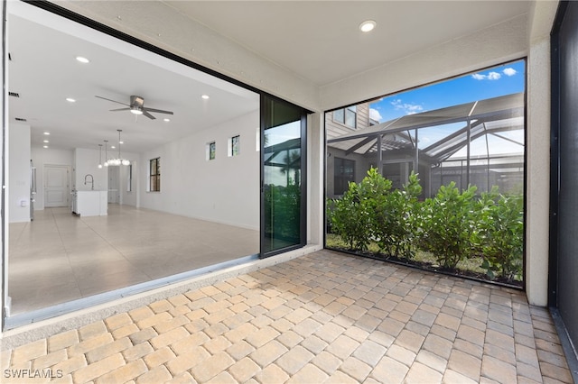 unfurnished sunroom featuring ceiling fan with notable chandelier