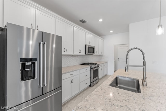 kitchen featuring high end appliances, decorative light fixtures, sink, and white cabinets