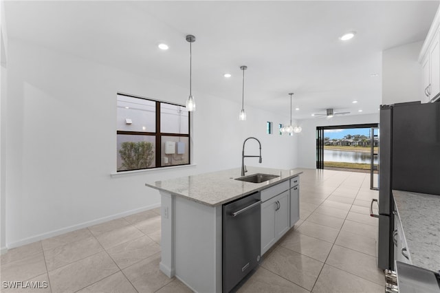 kitchen featuring an island with sink, sink, white cabinets, light stone counters, and stainless steel appliances