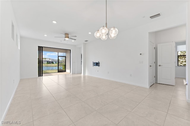 unfurnished room featuring a healthy amount of sunlight, ceiling fan with notable chandelier, and light tile patterned floors