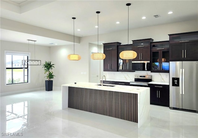 kitchen with sink, decorative light fixtures, stainless steel appliances, a kitchen island with sink, and backsplash