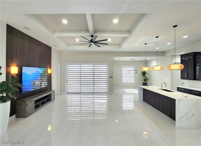 kitchen featuring sink, hanging light fixtures, a spacious island, light stone counters, and coffered ceiling