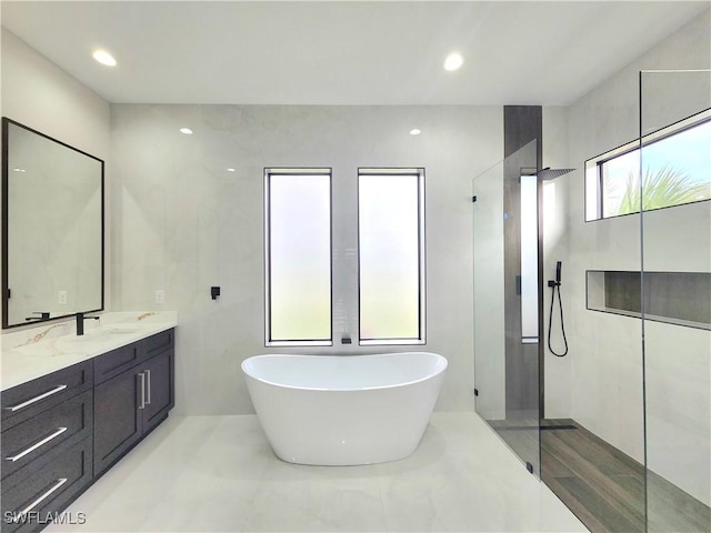 bathroom with vanity, separate shower and tub, and tile walls