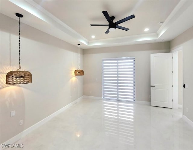 empty room featuring ceiling fan and a tray ceiling