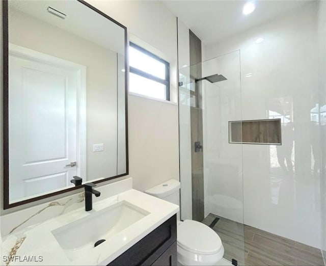 bathroom with tiled shower, vanity, and toilet