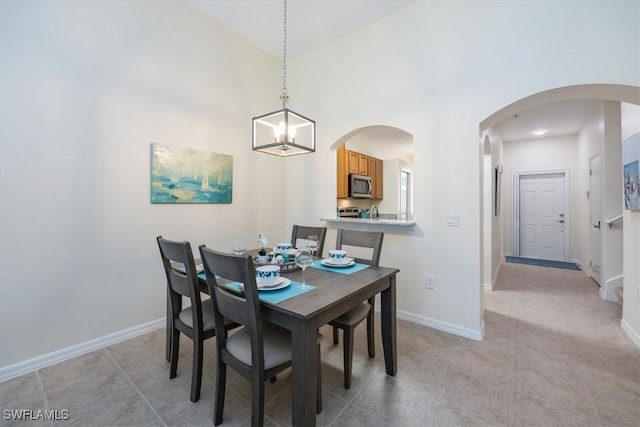 tiled dining area featuring high vaulted ceiling