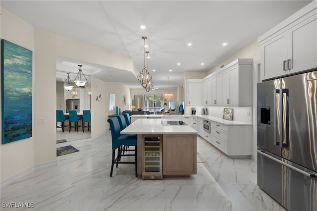 kitchen featuring white cabinetry, appliances with stainless steel finishes, a kitchen bar, and beverage cooler