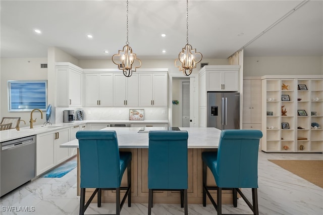 kitchen featuring white cabinetry, appliances with stainless steel finishes, a center island, and sink