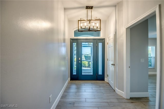 entrance foyer featuring an inviting chandelier, plenty of natural light, and light wood-type flooring