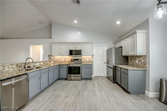 kitchen featuring appliances with stainless steel finishes, pendant lighting, sink, white cabinets, and light hardwood / wood-style floors