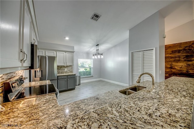 kitchen featuring sink, appliances with stainless steel finishes, an inviting chandelier, tasteful backsplash, and vaulted ceiling