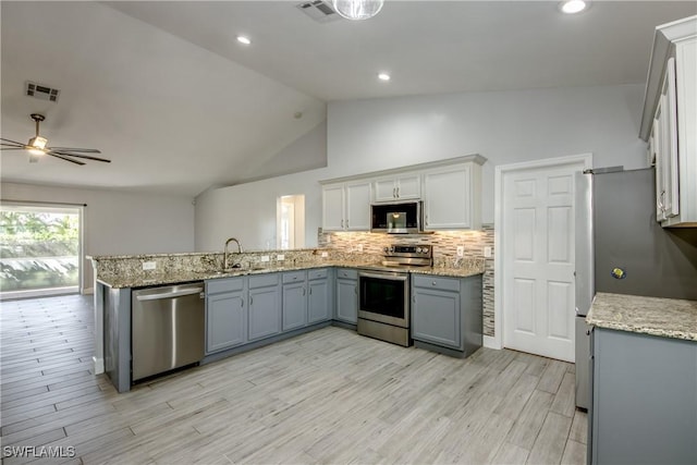 kitchen featuring appliances with stainless steel finishes, sink, backsplash, and kitchen peninsula