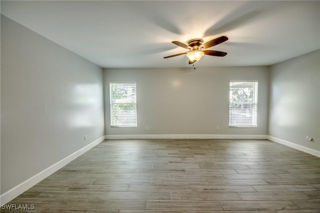 empty room with a wealth of natural light, ceiling fan, and light wood-type flooring