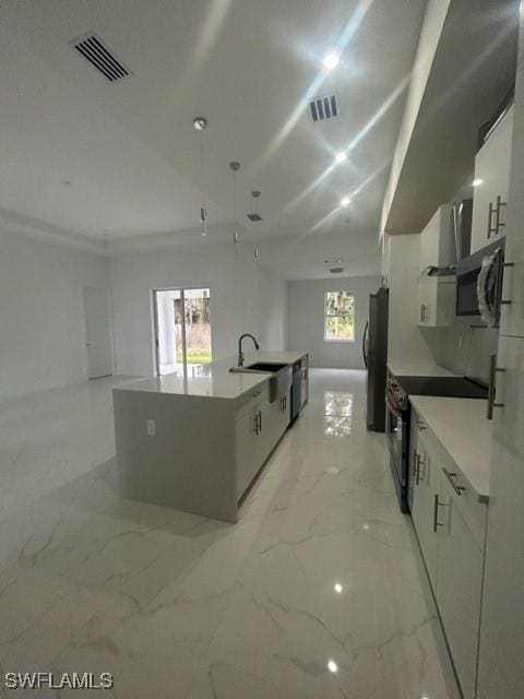 kitchen with appliances with stainless steel finishes, sink, a center island with sink, and white cabinets