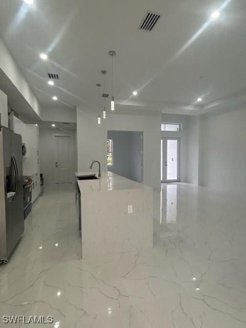 kitchen featuring decorative light fixtures, white cabinetry, a kitchen island with sink, stainless steel refrigerator with ice dispenser, and electric stove