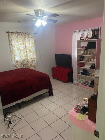 bedroom with a textured ceiling, ceiling fan, and light tile patterned flooring